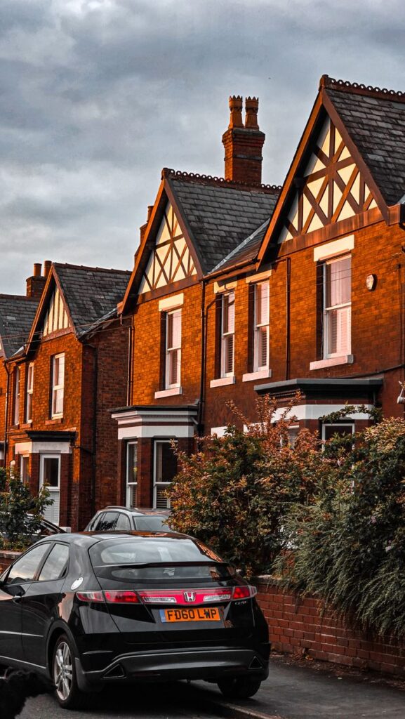 Row of traditional English townhouses with a black car parked on a serene street.