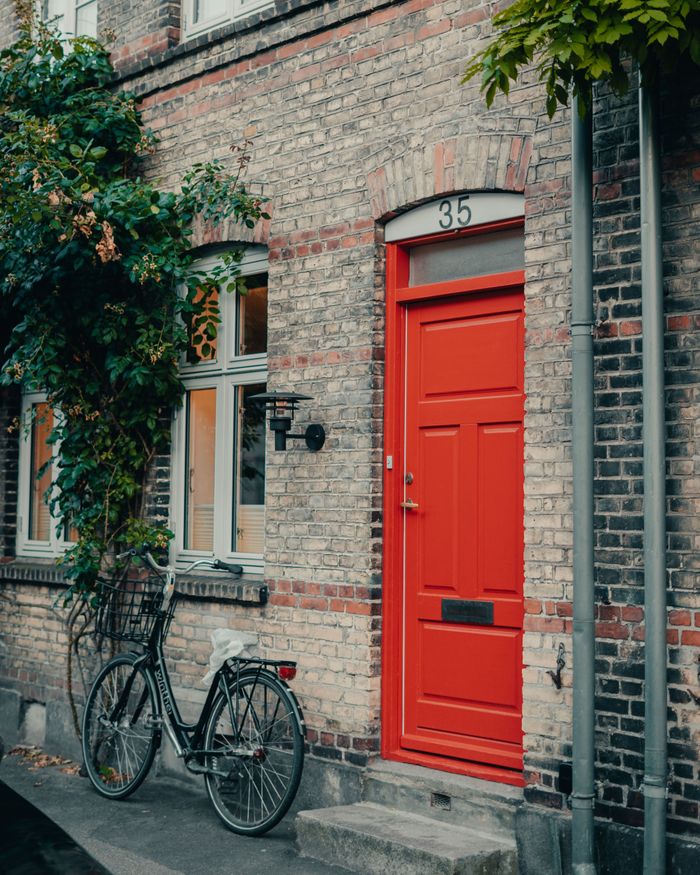 Brick building facade with a red door and bicycle in Copenhagen, Denmark.